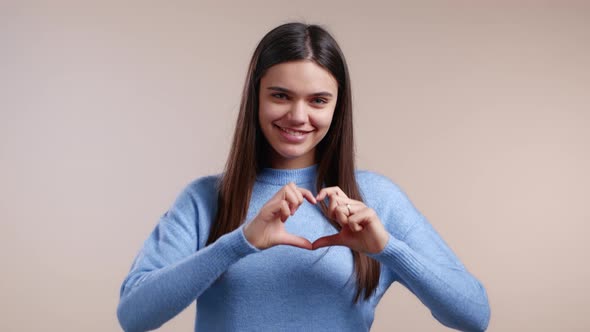 Kind Pretty Woman Making Sign of Shape Heart Near Her Chest