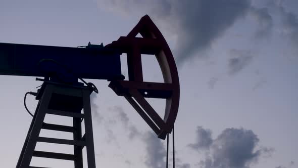 Oil Rig Stands in a Field at Sunset and Extracts Minerals