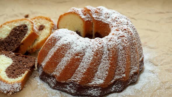 Home made freshly baked whole marble cake covered with powdered sugar on paper.