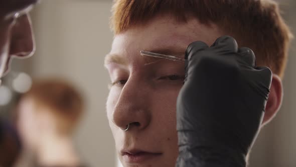 A Man Eyebrow Master Applying the Straightening Remedy on the Brow Hairs