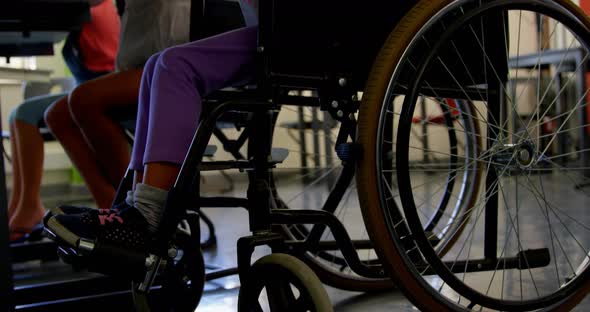 Disabled African american schoolgirl studying at desk in classroom at school 4k