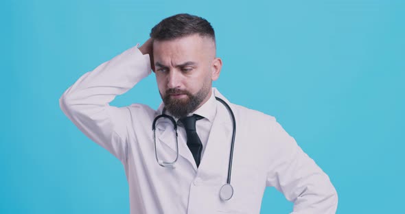 Pensive Medical Doctor Thinking About Patient Diagnosis, Scratching Head, Blue Studio Background