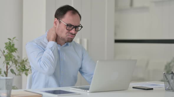 Middle Aged Man Having Neck Pain While Typing on Laptop