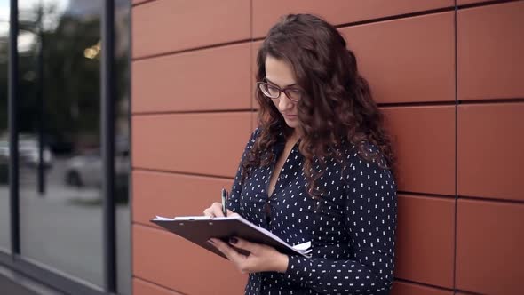 Young Businesswoman Writing Notes Standing Next to Office