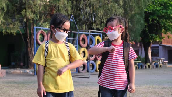 New Normal greeting. Children wearing disposable masks and bumping elbows greet each other at school