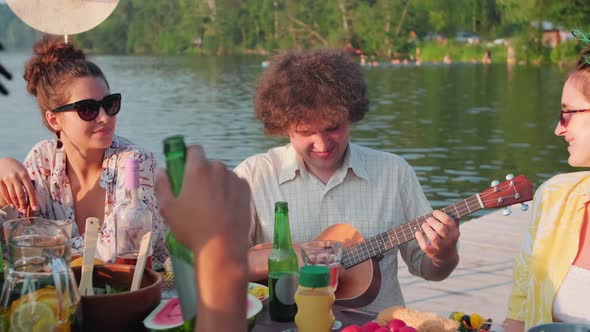 Joyous Man Playing Ukulele at Summer Party with Friends