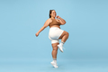Young, positive, smiling overweight woman sportswear doing cardio exercises on blue background - PhotoDune Item for Sale