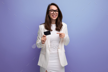 portrait of a young woman with dark hair in a white dress holding a money card for shopping