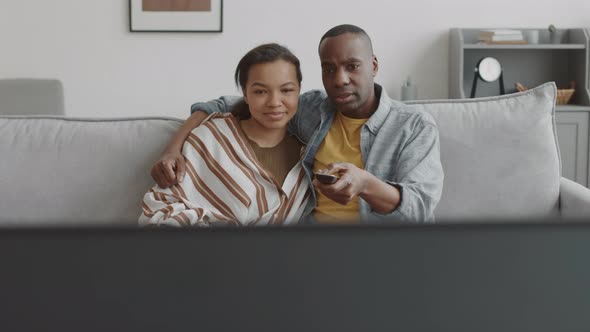 Multiethnic Couple Watching TV and Hugging