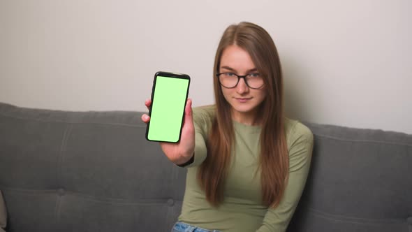 Pretty Smiling Caucasian Businesswoman in Glasses Showing Smartphone with Green Screen Chromakey