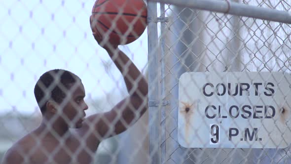 A young man playing basketball on a rainy day.