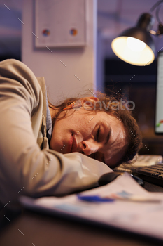  table after working overhours at financial strategy to increase company profit. Tired manager falling asleep in startup office. Corporate concept