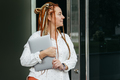 Young woman with red dreadlocks standing at the door of a building with laptop. - PhotoDune Item for Sale