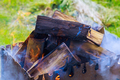 A small folding portable brazier filled with burning wood is placed in front of the BBQ grill during - PhotoDune Item for Sale