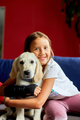 Happy teenage girl lying on sofa and embracing her puppy golden retriever - PhotoDune Item for Sale