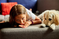 Happy teenage girl lying on sofa and embracing her puppy golden retriever - PhotoDune Item for Sale