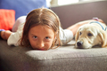 Happy teenage girl lying on sofa and embracing her puppy golden retriever - PhotoDune Item for Sale