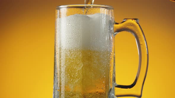 Jet of Beer is Poured Into a Wet Beer Glass with a Lot of Bubbles and Foam