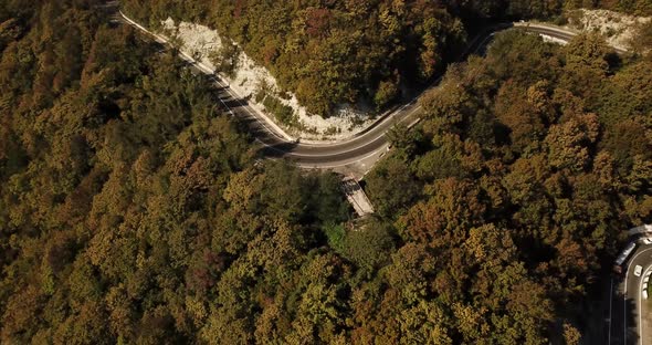 Aerial View of Car Driving Along The Winding Mountain Pass Road Through The Forest Trees. Autumn