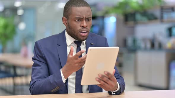 African Businessman Reacting to Loss on Tablet in Office