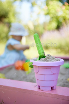 pink bucket and green scoop in the sandbox.