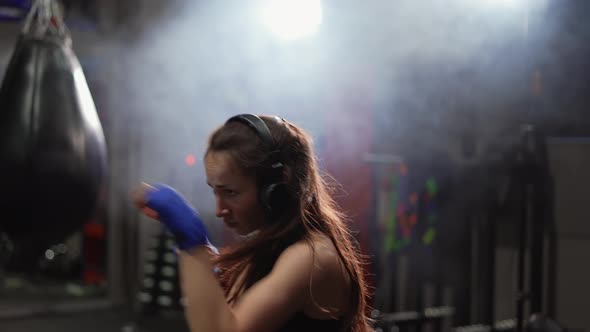 Concentrated Boxer Performing Active Punching in Bandages Wearing Headphones