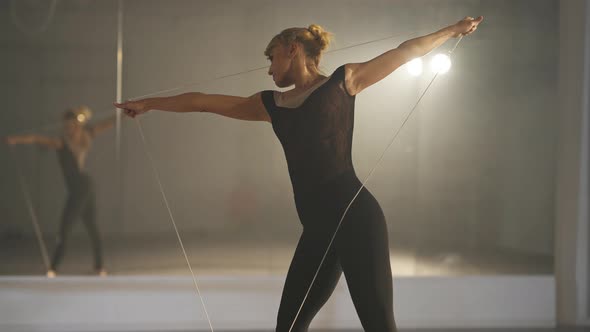 Medium Shot of Slim Ballet Dancer Training Holding Rope in Triangle Reflecting in Mirror