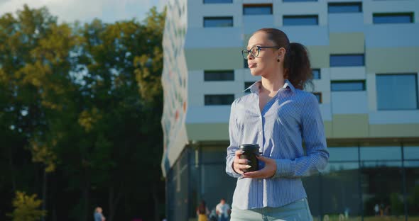 A Businesswoman is Standing with a Cup of Coffee Near the Business Center