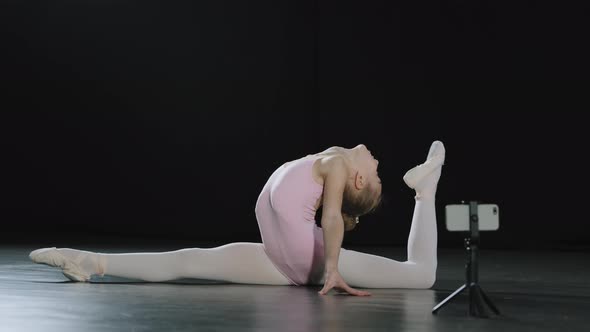 Teenager Ballerina Girl Gymnast Acrobat Sits in Twine Doing Back Bend Shoots Video Blog Vlog Online