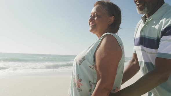 Portrait of smiling senior african american couple embracing on sunny beach