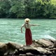 Young beautiful vintage woman in long skirt and straw hat dancing on stones near mountain river - VideoHive Item for Sale