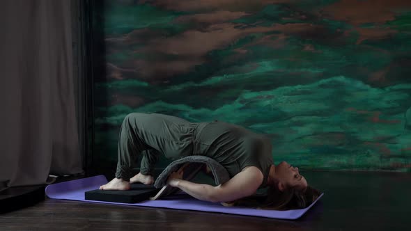 a Woman in a Green Jumpsuit is Lying on a Sports Mat