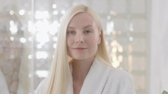Young Caucasian Woman With Long Blond Hair Wearing a Bath Towel Looking at Camera in a Bright