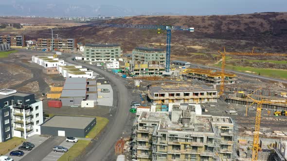 Aerial View Of Ongoing Construction Of Buildings With Yellow Tower Cranes At Daytime.