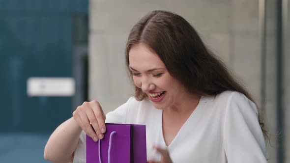 Young Caucasian Girl Woman Exited Lady Receiving Purple Package Gift Bag From Unknown Person Looking