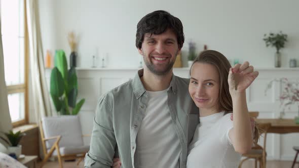 Young Couple Holds Happily a Key To Their New Home