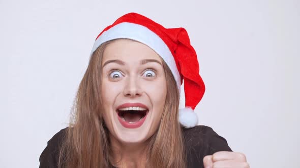 Cheerful Excited Young Pretty Fairhaired Girl in Christmas Hat Screaming Over White Background Slow