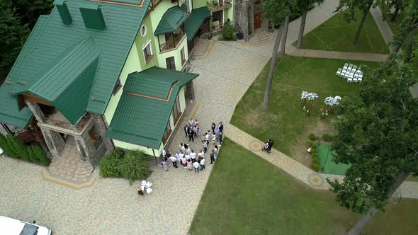 Many people are standing near houses with green tiled roofs in the middle of the forest