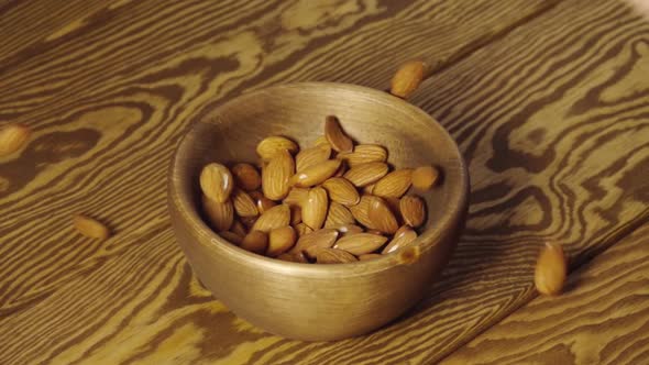 SLOW: Almond Kernels Fall Into A Wooden Dish On A Table