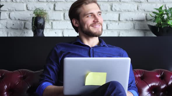 Smiling young businessman using laptop notebook working on table at home, happy man surfing web look