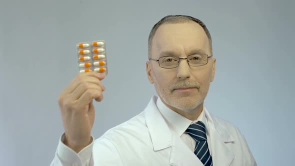 Experienced Doctor Showing Pack of Capsules for Camera, Pharmaceutical Industry