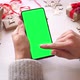 Woman holding smartphone with green screen and touch on screen on Christmas background - VideoHive Item for Sale