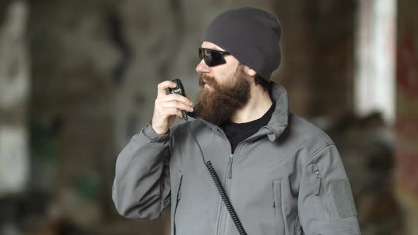 Seriouslooking Bearded Man in Sunglasses Using Walkie Talkie
