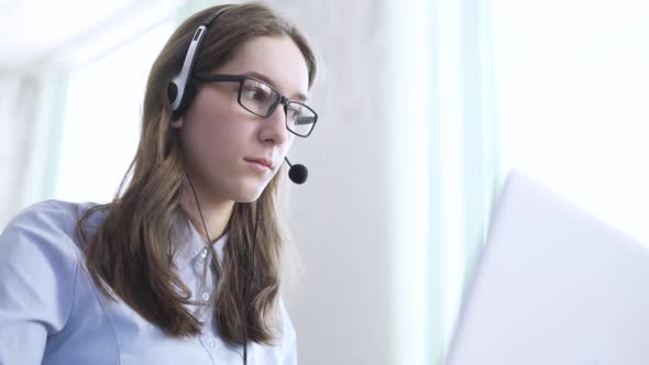 Serious Call Center Operator in Wireless Headset Talking with Customer Close Up