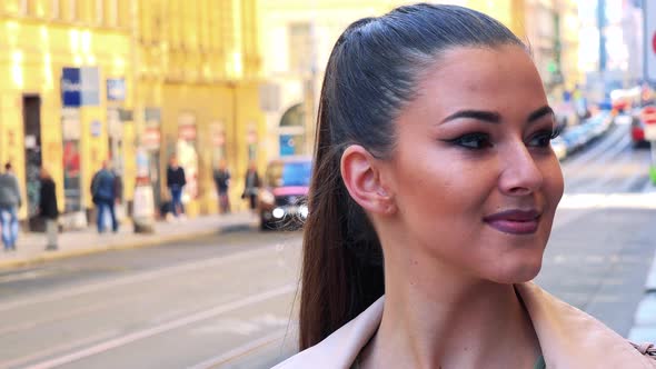 Young Beautiful Woman Looks Around in the City - Street in the Background