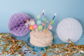 Homemade cream cake with candles. Party decor with paper balloons with fringe. - PhotoDune Item for Sale