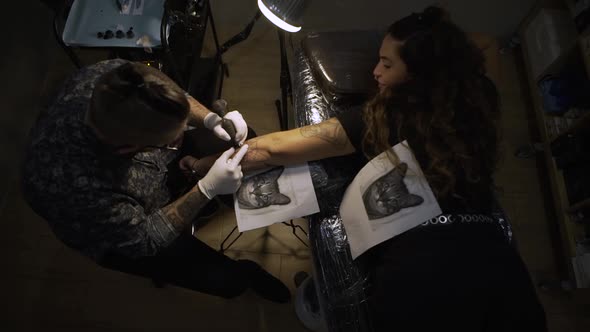 Young master making tattoo on skin of client