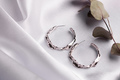 Creative composition with simple silver jewelry earrings set on silk background with dried flowers - PhotoDune Item for Sale