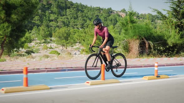 Professional female cyclist hard training on bicycle on bike lane path along green park. 