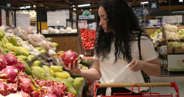 Woman Makes Purchases in the Supermarket Healthy Food Dragon Fruit Puts in a Basket to Be Weighed on